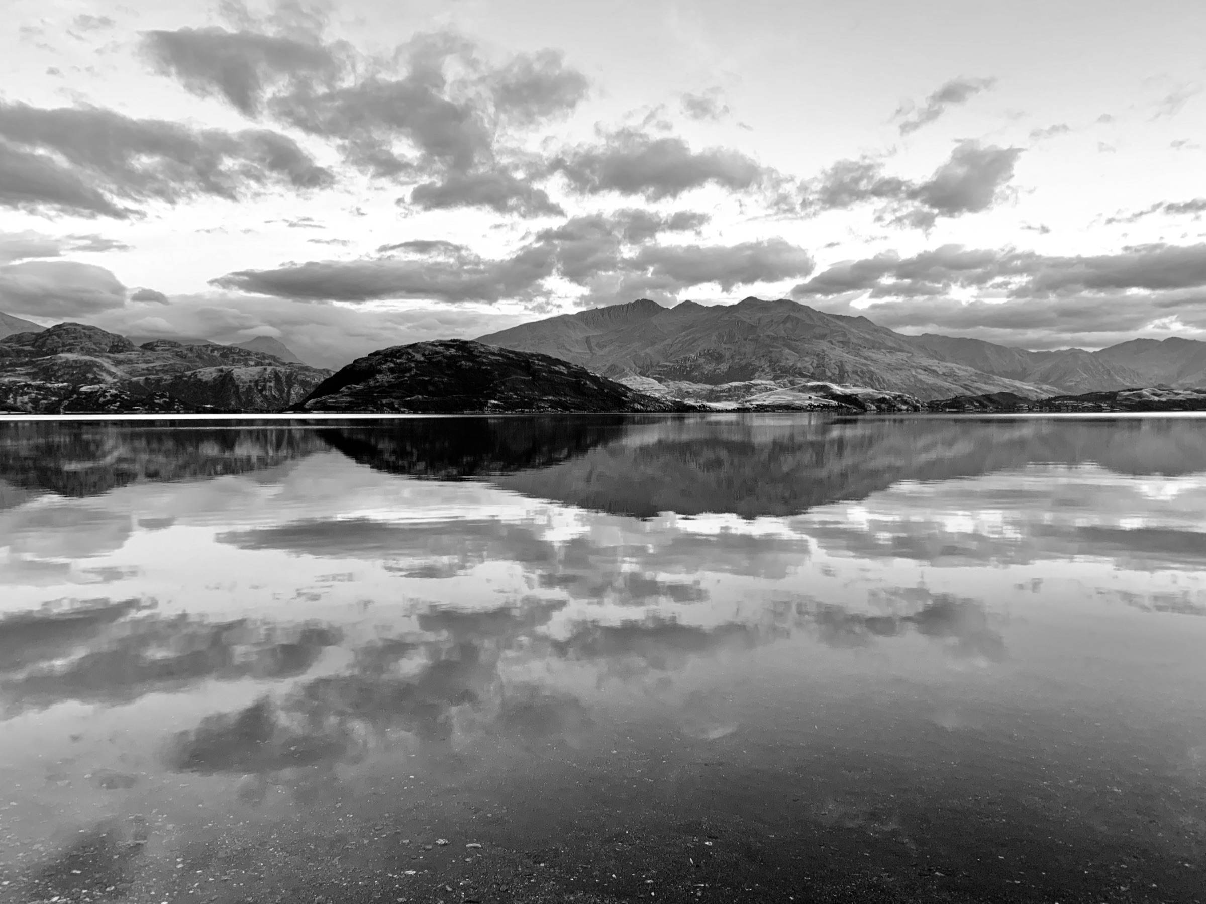 Mountains and clouds reflected in still lake water